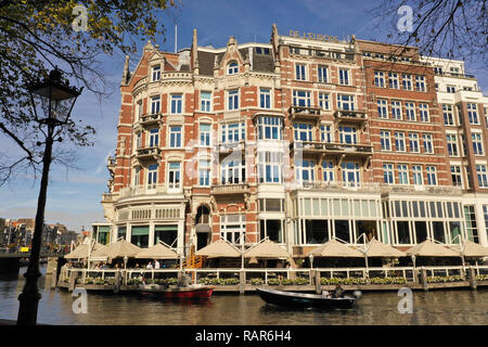 Eine der wunderschönen Gebäude von Amsterdam: L'Europe Amsterdam Hotel, mit Booten, vorbei an der Amstel Stockfoto