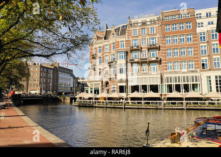 Eine der wunderschönen Gebäude von Amsterdam: L'Europe Amsterdam Hotel, mit Booten, vorbei an der Amstel Stockfoto