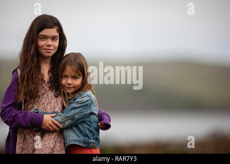 Zwei Mädchen Hug, wie sie für ein Portrait außerhalb dar. Stockfoto
