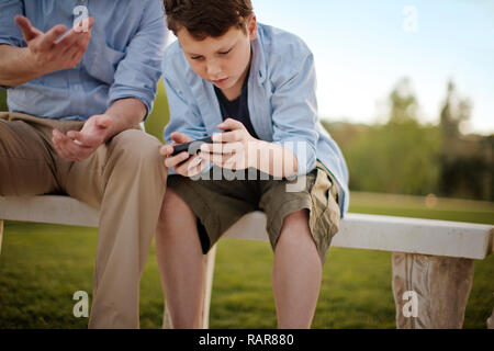 Junge spielt mit seinen Vätern iphone. Stockfoto