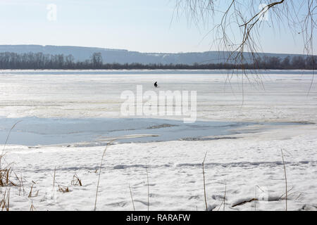 Ein Mann im Winter angeln im Fluss im frühen Frühjahr Stockfoto