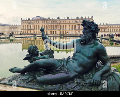 Bronze Skulptur im Garten von Schloss Versailles bei Paris, Frankreich mit dem Spiegelbild im Brunnen Wasser.