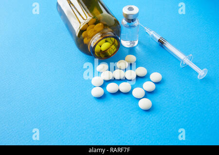 Braune Glasflasche mit weißen Pillen und eine Spritze mit einer pharmazeutische Zubereitung auf dem Tisch. Stockfoto