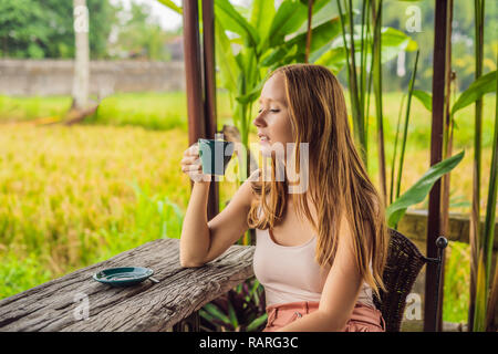 Frau mit einer Tasse Kaffee auf der Veranda Cafe in der Nähe der Reisterrassen auf Bali, Indonesien Stockfoto