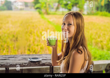 Junge Frau mit Schale Matcha Latte, Grüner Tee, auf alten hölzernen Hintergrund Tabelle Stockfoto