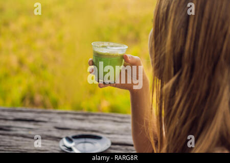 Junge Frau mit Schale Matcha Latte, Grüner Tee, auf alten hölzernen Hintergrund Tabelle Stockfoto