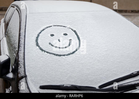 Graffiti im Schnee auf der Windschutzscheibe des Autos Stockfoto