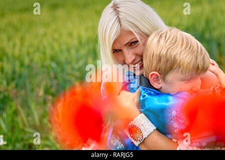 Mutter mit ihrem Sohn in einer herrlichen Wiese. Der Junge schließt seine Mutter fest und liebevoll. Stockfoto