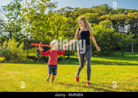 Mutter und Sohn spielen mit einem großen Modell Spielzeug Flugzeug im Park Stockfoto