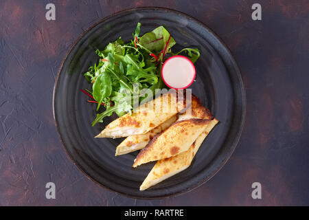 Dünne Pfannkuchen mit Schinken und Käse mit Spinat, Rucola, Mais und Mangold Salat serviert. Stockfoto