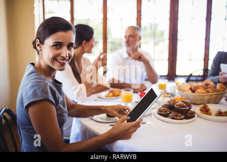 Geschäftsfrau, die an der Kamera, während mit digitalen Tablet Stockfoto