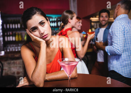 Verärgert Frau am Tisch sitzend in Nachtclub Stockfoto