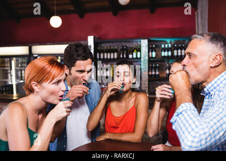 Freunde trinken Tequila am Tisch Stockfoto