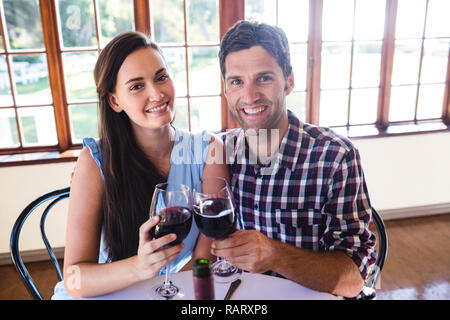 Paar toasten Rotwein Glas im Restaurant Stockfoto