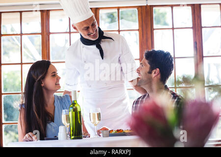 Koch im Gespräch mit paar im restaurant Stockfoto