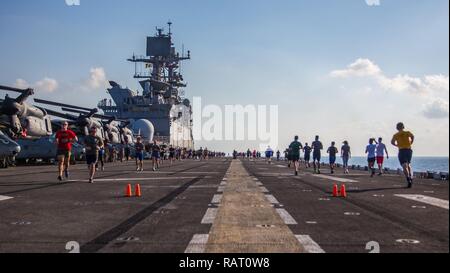 USS Makin Island, Golf von Aden (Feb. 13, 2017) U.S. Marines und Matrosen mit der Makin Island Amphibious Ready Gruppe/11 Marine Expeditionary Unit in einer halben Marathon Rennen an Bord der USS Makin Island (LHD8) in den Golf von Aden, 13.02.beteiligen. Marinesoldaten und Matrosen lief 42 Runden auf dem Flugdeck der USS Makin Island und Erfrischungen während der Rennen zur Verfügung gestellt. Die 11 MEU unterstützt derzeit Mission US 5 Flotte zur Förderung von Stabilität und Sicherheit und in der Region pflegen, während im Gange während ihrer West-Pac 16-2 Bereitstellung. Stockfoto