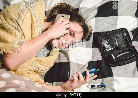 Thema Diabetes. junge Frau home Schlafzimmer Bett verwendet die Technologie gerät Messung der Blutzuckerwerte, glucometer Teststreifen hohe Blutzuckerspiegel Krankheit. C Stockfoto