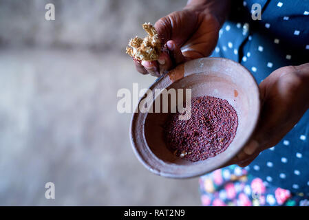 Sorghum Körner in Houten in die Hände der Sri Lankan Frau Stockfoto