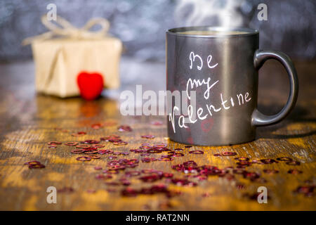 Valentinstag Konzept mit schwarzer Schale, Kreide Inschrift auf einer Tasse und einem roten Herz. Stockfoto