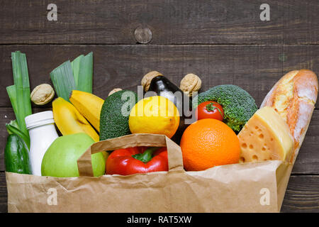 Full Paper bag verschiedener gesundes Essen auf rustikalen Holzmöbeln Hintergrund. vegetarisches Essen. Ansicht von oben. Flach Stockfoto