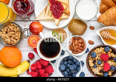 Frühstück serviert mit Kaffee, Orangensaft, Toast, Croissants, Müsli, Milch, Nüssen und Früchten. Ausgewogene Ernährung. gesund essen Top View Stockfoto