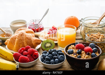 Frühstück serviert mit Kaffee, Orangensaft, Toast, Croissants, Müsli, Milch, Nüssen und Früchten. Ausgewogene Ernährung. gesund essen Nahaufnahme Stockfoto