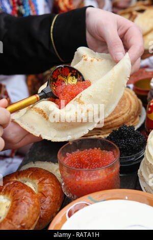 Die Hand Kaviar auf Pfannkuchen Stockfoto