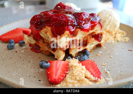 Geschlossen bis eine Platte von Waffel mit erdbeersauce, frische Beeren und Vanille Eis Stockfoto