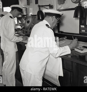 1950, historische, an Bord der Union-Castle Steamship, zwei Uniformierte navigation Offiziere in den Kontrollraum mit Diagrammen arbeiten, die Bewegungen des Schiffes, Position und Richtung verfolgen. Stockfoto