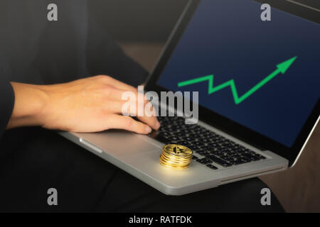Geschäftsmanns, der auf dem Laptop mit einem goldenen bitcoin Münzen auf it-Stack. Grüne Karte, Preis steigen. Stockfoto