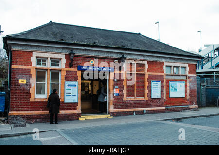 Frau draußen Stonebridge Park Tube Station mit einem bewölkten Himmel. Stockfoto