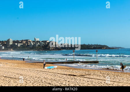 Morgen Dunst an der Manly Beach mit Surfer vorbereiten für die Wellen auf eine perfekte blau Sommertag in eine stimmungsvolle Landschaft (Sydney, Australien) Stockfoto