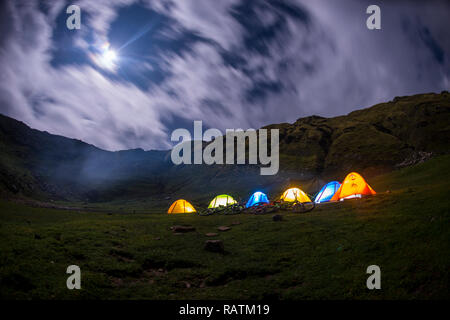 Eine Reihe von Zelten nachts auf Khalia oben über der Stadt Munsyari in Uttarakhand, Indien Himalaya. Die Panchchuli gipfeln in der Ferne. Stockfoto