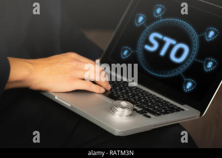 Security Token bietet (STO) Text auf einem Laptop Bildschirm gehalten von einem Geschäftsmann mit einem Stapel des Astraleums Stockfoto