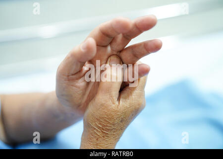 Asiatische Senior oder ältere alte Frau Patienten schmerzen Finger und Hand beim Sitzen auf dem Bett in der Krankenpflege Krankenhaus: Gesunde starke medizinische Konzept. Stockfoto