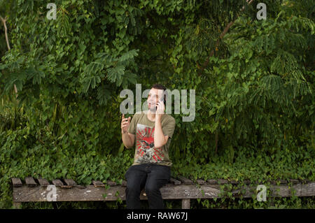 Mann mittleren Alters spricht in der Natur auf dem Handy. Stockfoto