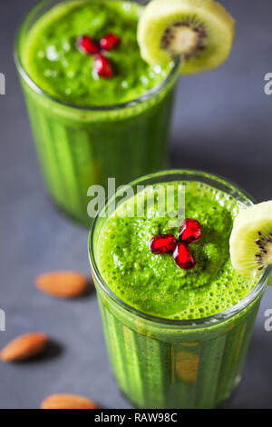 Grüne Smoothie mit Kiwi, Apfel, Spinat, Banane und Mandelmilch Nahaufnahme mit Granatapfel Körner eingerichtet Stockfoto