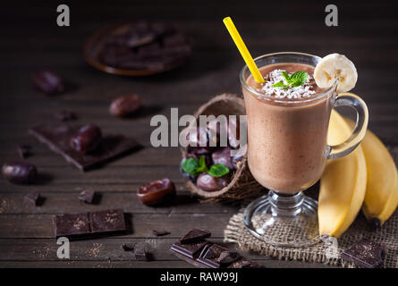 Süße Schokolade Banane Smoothie mit Kokosmilch und Termine mit Minze auf hölzernen Hintergrund Stockfoto
