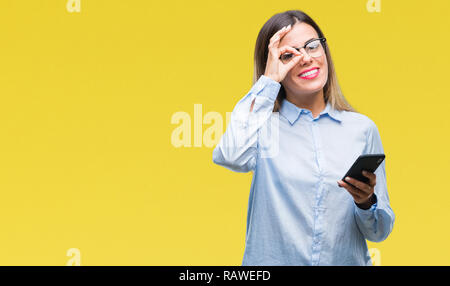 Junge schöne Geschäftsfrau SMS-Nachricht mit dem Smartphone über isolierte Hintergrund mit glücklichen Gesicht lächelnd tun ok Zeichen mit der Hand auf Auge lookin Stockfoto