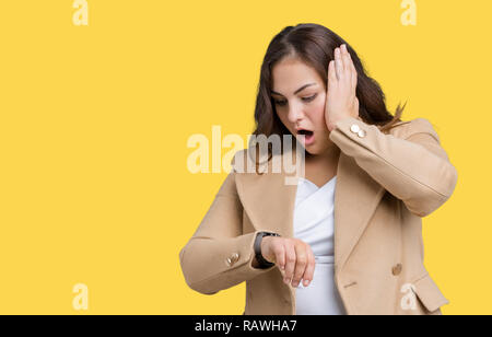 Schöne Übergrößen junge Frau tragen Winter Mantel über isolierte Hintergrund ein Blick auf die Uhr Zeit Sorgen, Angst, sich spät Stockfoto