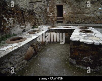 Italien. Herculaneum. Alte römische Stadt, die vom Ausbruch des Vesuv im Jahr 79 N.CHR. zerstört. Counter Bar mit Löchern, wo Gläser (dolia) für essen oder Wein eingestellt wurden. Kampanien. Stockfoto