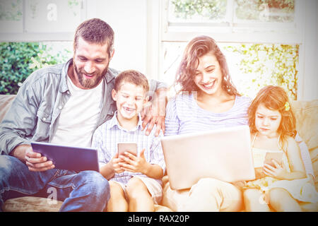 Familie mit Hilfe von Technologien sitzend auf sofa Stockfoto