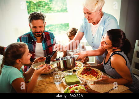 Ältere Frau servieren Mahlzeit zu ihrer Familie Stockfoto