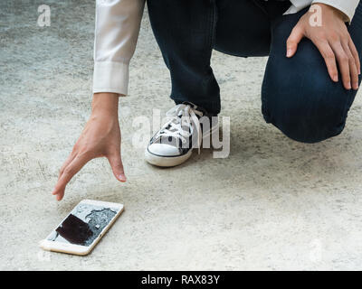 Person Kommissionierung gebrochen Smart Phone (Risse) der Boden Stockfoto