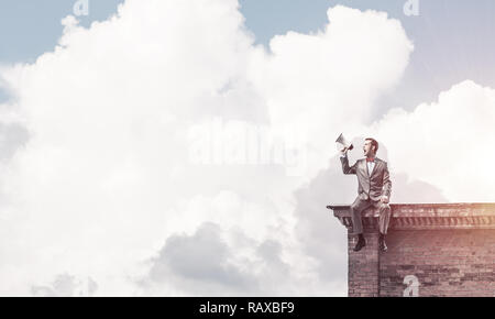 Unternehmer oder Manager auf dem Dach des Gebäudes etwas verkünden in Stockfoto