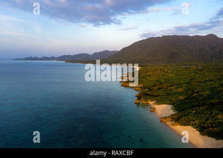 Luftaufnahme über einzigartige tropische Insel mit Berge, einsame weisse Sandstrände und Coral Reef, bei Sonnenuntergang, von Drohne, Ishigaki, Japan Stockfoto