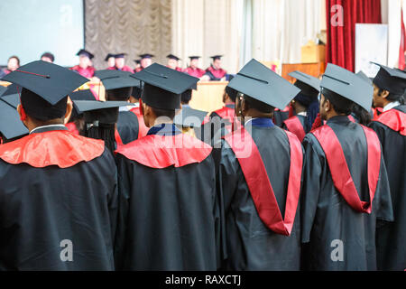 Ausländische Medizinstudenten in eckigen akademische Graduierung Kappen und schwarze Regenmäntel während der Aufnahme Stockfoto