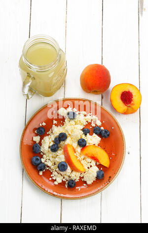 Stillleben mit Hüttenkäse, Smoothie, Heidelbeere und Pfirsich auf weißem Holz- Hintergrund Stockfoto