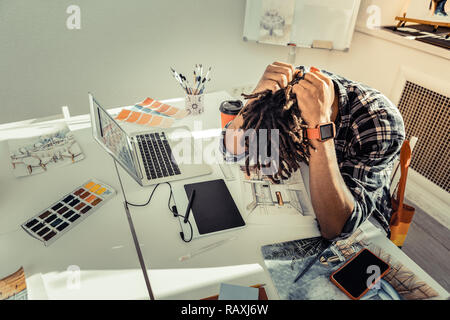 Dunkelhaarige Künstlerin mit Dreadlocks Gefühl extrem erschöpft Stockfoto