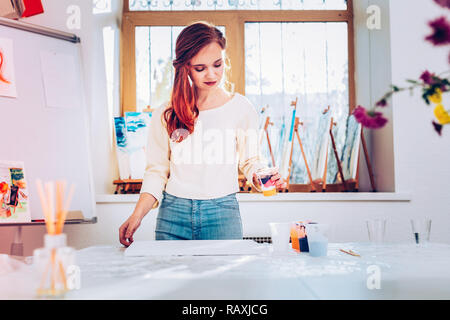 Kunst Lehrer in Jeans und T-Shirt beige stehend in der Malerei studio Stockfoto